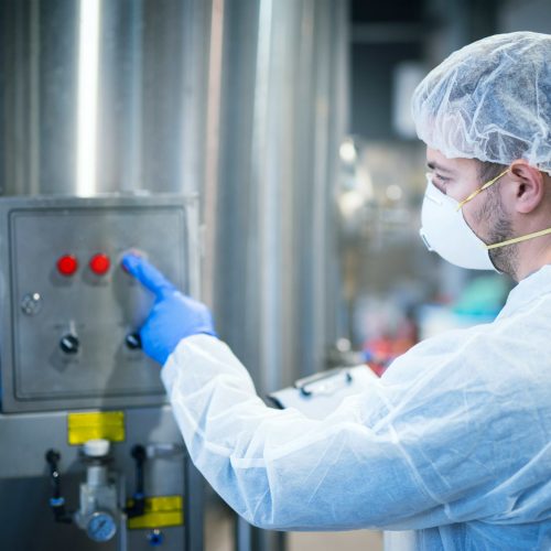 technologist-white-protective-uniform-with-hairnet-mask-operating-industrial-machine-food-processing